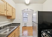 Thumbnail 10 of 21 - A kitchen with a black refrigerator and a stove top oven.