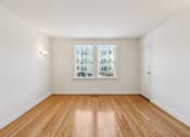 Thumbnail 9 of 17 - A room with wooden flooring and a window showing a view of a building.