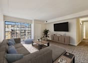Thumbnail 9 of 43 - A living room with a grey couch and a flat screen TV mounted on the wall.