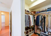 Thumbnail 4 of 18 - A walk in closet with clothes and shoes.