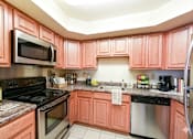 Thumbnail 1 of 18 - A kitchen with pink cabinets and stainless steel appliances.
