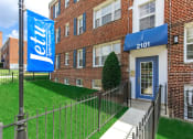 Thumbnail 1 of 16 - exterior of jetu apartments with lush landscaping, brick building and sidewalk in washington dc