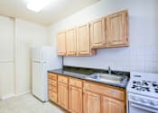 Thumbnail 3 of 21 - kitchen with tile floorings, wood cabinetry, refrigerator and gas range at 3151 mount pleasant apartments in washington dc