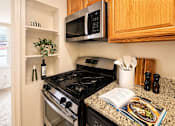 Thumbnail 3 of 17 - A kitchen with a black stove and a black microwave above it.