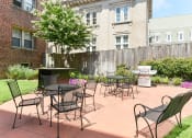 Thumbnail 22 of 33 - courtyard with table, chairs, grilling area and lush landscaping at meridian park apartments in washington dc