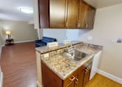 Thumbnail 9 of 21 - A kitchen with a granite countertop and wooden cabinets.