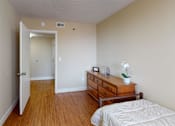 Thumbnail 11 of 21 - A bedroom with a bed, dresser, and open door leading to another room.