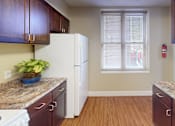 Thumbnail 8 of 21 - A kitchen with brown cabinets and a white fridge.
