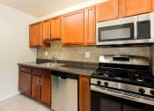 Thumbnail 1 of 13 - a kitchen with stainless steel appliances and wooden cabinets at penn view apartments in washington dc