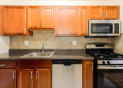 Thumbnail 2 of 13 - a kitchen with wooden cabinets and a sink and a stove at penn view apartments in washington dc