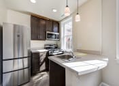 Thumbnail 1 of 28 - kitchen with espresso cabinetry, breakfast bar and stainless steel appliances at petworth station apartments in washington dc