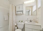Thumbnail 4 of 17 - A white bathroom with a toilet, sink, and shower.
