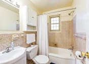 Thumbnail 7 of 22 - A white toilet sits in a bathroom with a white sink and a white bathtub.