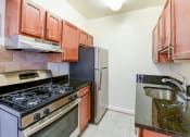 Thumbnail 1 of 20 - kitchen with wood cabinetry, gas range, and stainless steel appliances sherry hall apartments in washington dc
