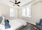 Thumbnail 11 of 28 - bedroom with bed, chair, large windows and ceiling fan at petworth station apartments in washington dc