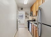 Thumbnail 2 of 17 - A kitchen with a white refrigerator, black dishwasher, and wooden cabinets.