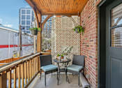 Thumbnail 11 of 17 - A small balcony with a table and chairs.