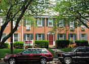 Thumbnail 12 of 17 - A red car is parked in front of a brick building.