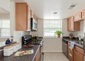 Thumbnail 1 of 20 - A kitchen with wooden cabinets and a black stove top oven.