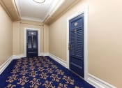 Thumbnail 11 of 25 - a corridor with two blue doors and a carpeted floor at the calverton apartments in washington dc