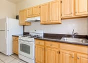 Thumbnail 13 of 25 - a kitchen with wooden cabinets and white appliances at the calverton apartments in washington dc
