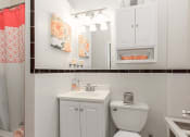 Thumbnail 9 of 25 - a bathroom with a sink, toilet and mirror at the calverton apartments in washington dc
