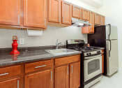 Thumbnail 2 of 25 - a kitchen with wooden cabinets and stainless steel appliances at the calverton apartment building in washington dc