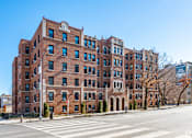 Thumbnail 49 of 64 - A large red brick building with many windows and a crosswalk in front.