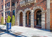 Thumbnail 48 of 64 - A brick building with a sign that says "Now Leasing" in front of it.