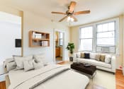 Thumbnail 7 of 22 - studio apartment showing sofa, bed, ceiling fan, large windows and view of kitchen at the foreland apartments in washinton dc