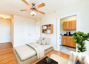 Thumbnail 9 of 22 - studio apartment showing sofa, bed, ceiling fan, large windows and view of kitchen at the foreland apartments in washinton dc