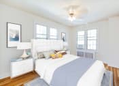 Thumbnail 9 of 29 - bedroom with bed, nightstands, large windows, hardwood flooring and ceiling fan at the frontenac apartments in washington dc