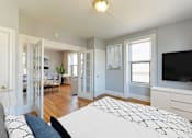 Thumbnail 8 of 21 - bedroom with bed, dresser, tv, hardwood flooring, french doors, and large windows at the shawmut apartments in washington dc