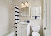 Thumbnail 36 of 36 - A white bathroom with a striped shower curtain.