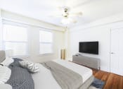 Thumbnail 7 of 28 - bedroom with bed, dresser, tv, hardwood floors, large windows , and ceiling fan at wakefield hall apartments in washington dc