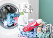 Thumbnail 16 of 18 - A laundry basket filled with clothes and detergent sits in front of an open washing machine.