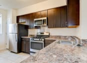 Thumbnail 4 of 14 - kitchen with espresso cabinetry, breakfast bar and stainless steel appliances at sheridan station south townhomes in washington dc