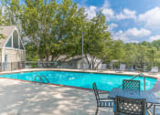Thumbnail 16 of 23 - a swimming pool with a table and chairs and a house in the background at Bradford Gwinnett Apartments, Georgia , 30071
