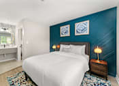 Thumbnail 17 of 41 - A bedroom with a white bed and a blue accent wall.