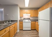 Thumbnail 24 of 35 - an empty kitchen with wood cabinets and white appliances at Crogman School Lofts, Atlanta