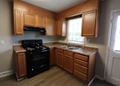 Thumbnail 34 of 39 - A kitchen with wooden cabinets and a black stove top oven.