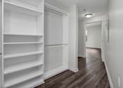 Thumbnail 12 of 34 - A long hallway with a white door and shelves on the left.
