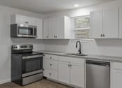 Thumbnail 4 of 28 - a kitchen with white cabinets and stainless steel appliances and a sink