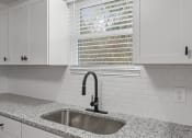 Thumbnail 7 of 28 - a kitchen with white cabinets and a sink and a window