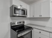 Thumbnail 6 of 28 - a kitchen with white cabinets and a stove and a microwave