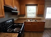 Thumbnail 36 of 39 - A kitchen with wooden cabinets and a black stove top oven.