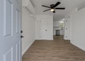 Thumbnail 18 of 28 - an empty living room with a ceiling fan and a kitchen