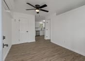Thumbnail 27 of 28 - an empty living room with a ceiling fan and a kitchen