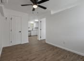 Thumbnail 14 of 28 - an empty living room with a ceiling fan and a kitchen