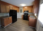 Thumbnail 39 of 39 - A kitchen with wooden cabinets and a black refrigerator.